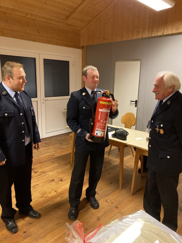 Ehrung für Joachim Neumeiers langjährigen Einsatz in der Feuerwehr und im Verein: Thomas Döhnel und Christian Thoma überreichen "Jockel"-Feuerlöscher.