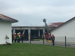 Brennende Lagerhalle in Hohenreichen mit Feuerwehrleuten, Drehleiter und ausgebranntem Teleskoplader.
